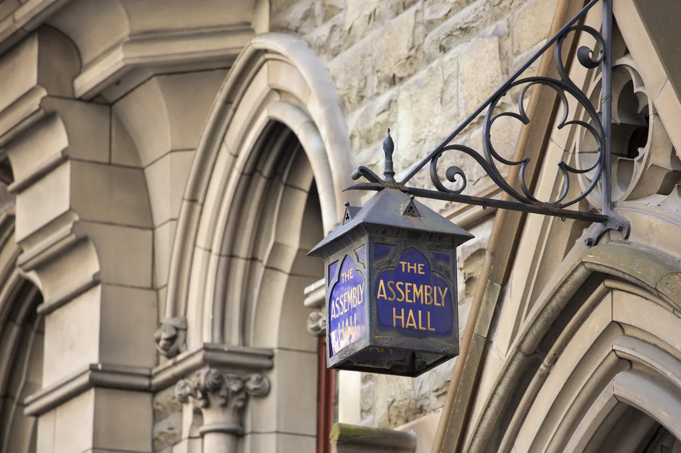 A lantern sign reading The Assembly Hall on the stone front of the building
